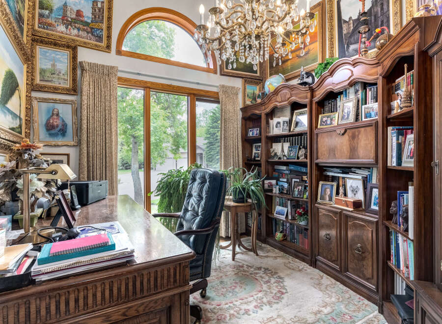 Step into this opulent home office, featuring a grand executive desk adorned with a vintage lamp and organized stationery.