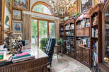 Step into this opulent home office, featuring a grand executive desk adorned with a vintage lamp and organized stationery.