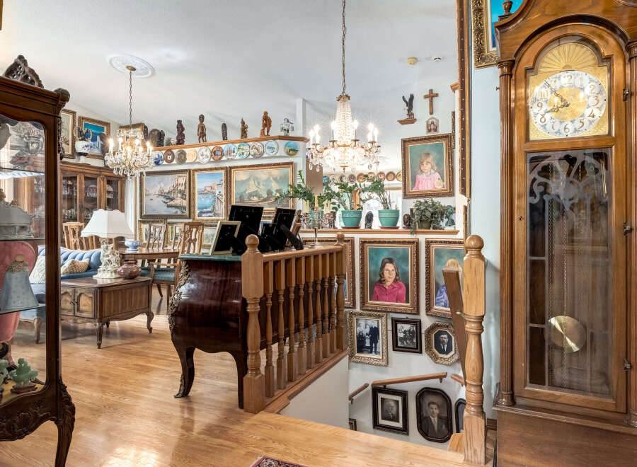 Step into a grand foyer featuring a stunning grandfather clock and a beautifully ornate staircase.