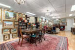 Step into this beautifully appointed room, featuring a large wooden dining table perfect for gatherings, surrounded by an impressive collection of framed artwork adorning the walls.