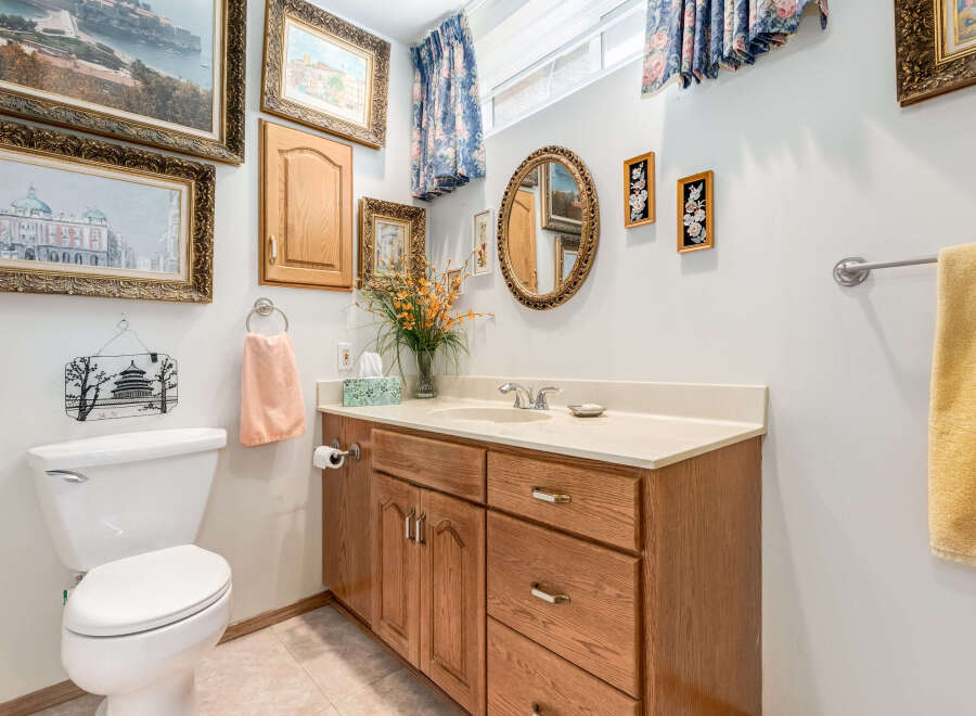 This charming bathroom features a classic wooden vanity with ample storage and a clean white countertop.