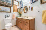 This charming bathroom features a classic wooden vanity with ample storage and a clean white countertop.