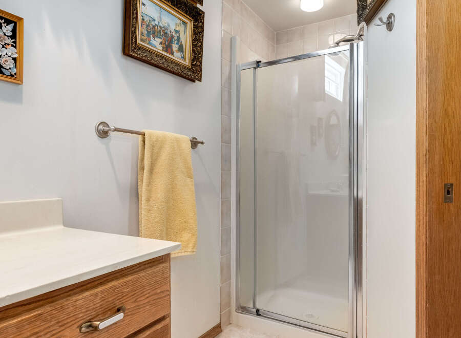This bathroom features a spacious shower with frosted glass doors, perfect for privacy.