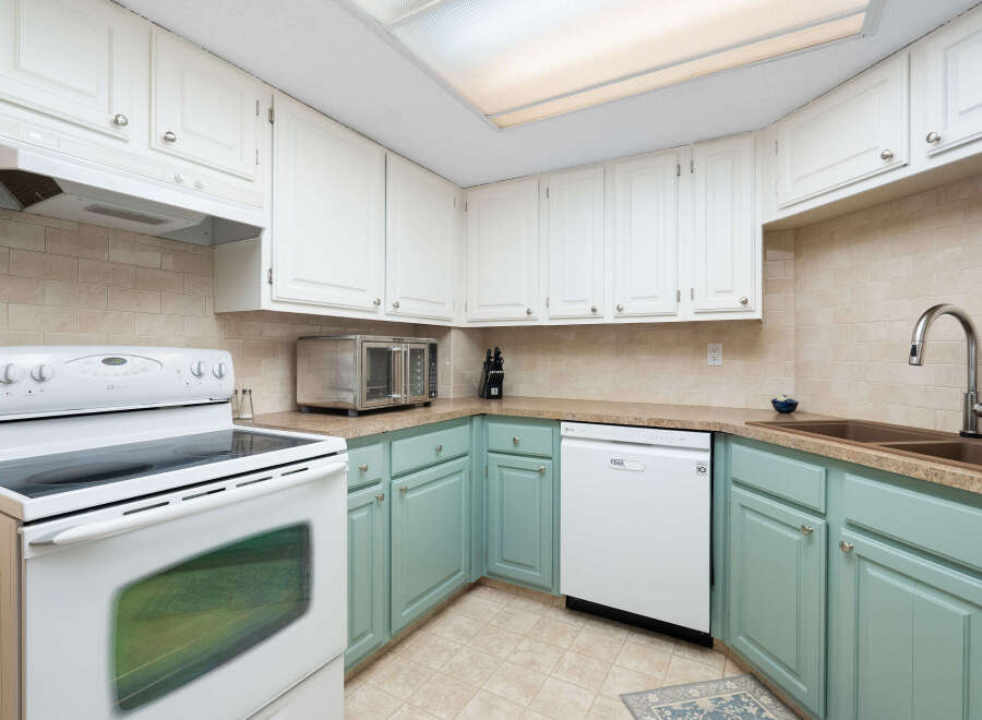 This charming kitchen features a white electric range with a smooth top and a built-in microwave above.