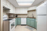 This charming kitchen features white upper cabinets and light teal lower cabinets, offering a bright and airy feel.