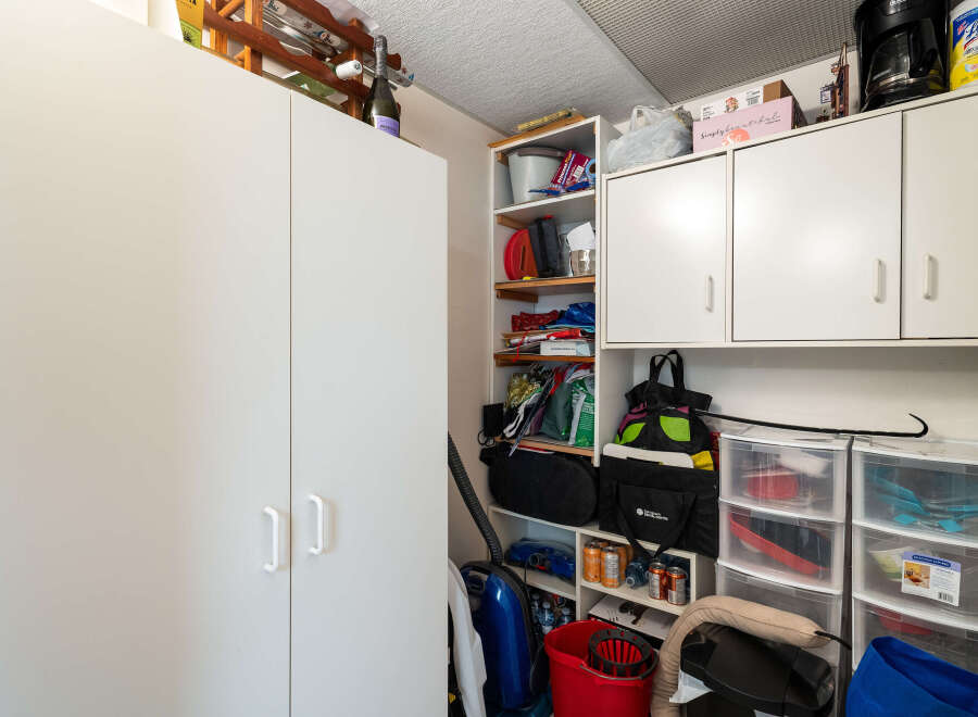 This spacious storage area offers ample room for all your belongings, featuring large white cabinets and open shelving units.