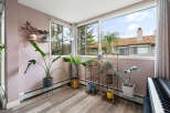 Bright and airy sunroom filled with lush greenery, featuring large windows that offer scenic views of the outdoors.