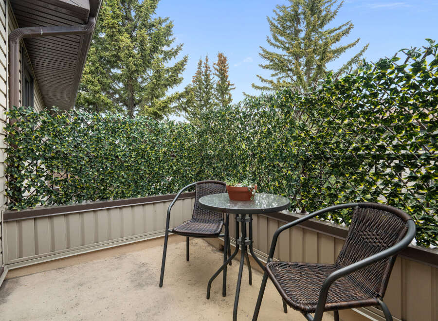 Enjoy your morning coffee or evening drink on this charming balcony, complete with a bistro set and a privacy screen of lush greenery.