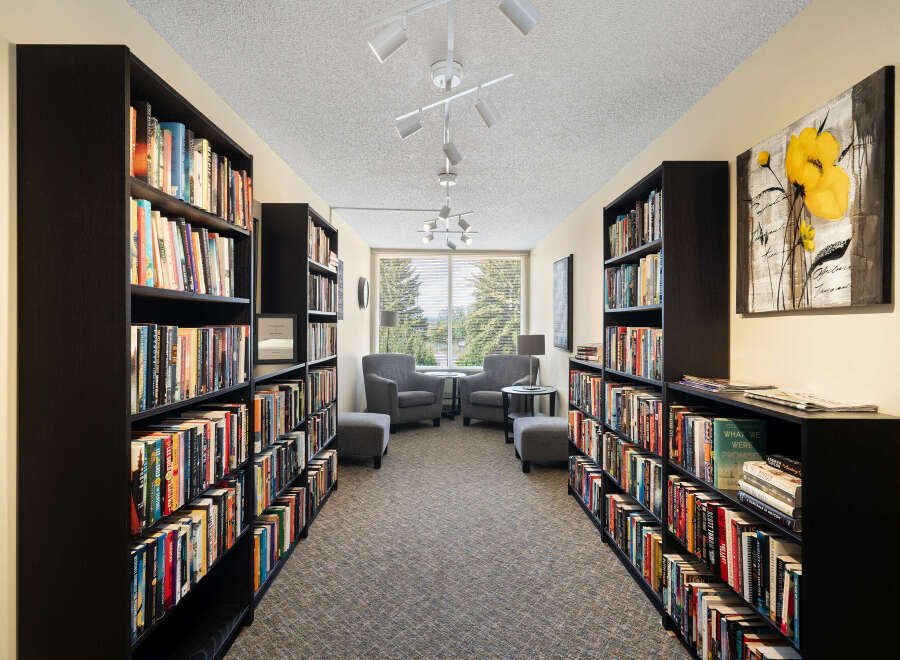 Step into this inviting library, featuring floor-to-ceiling bookshelves filled with a diverse collection of literature.