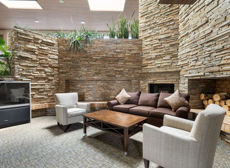 Experience cozy living in this inviting space featuring a rustic stone fireplace and comfortable seating.