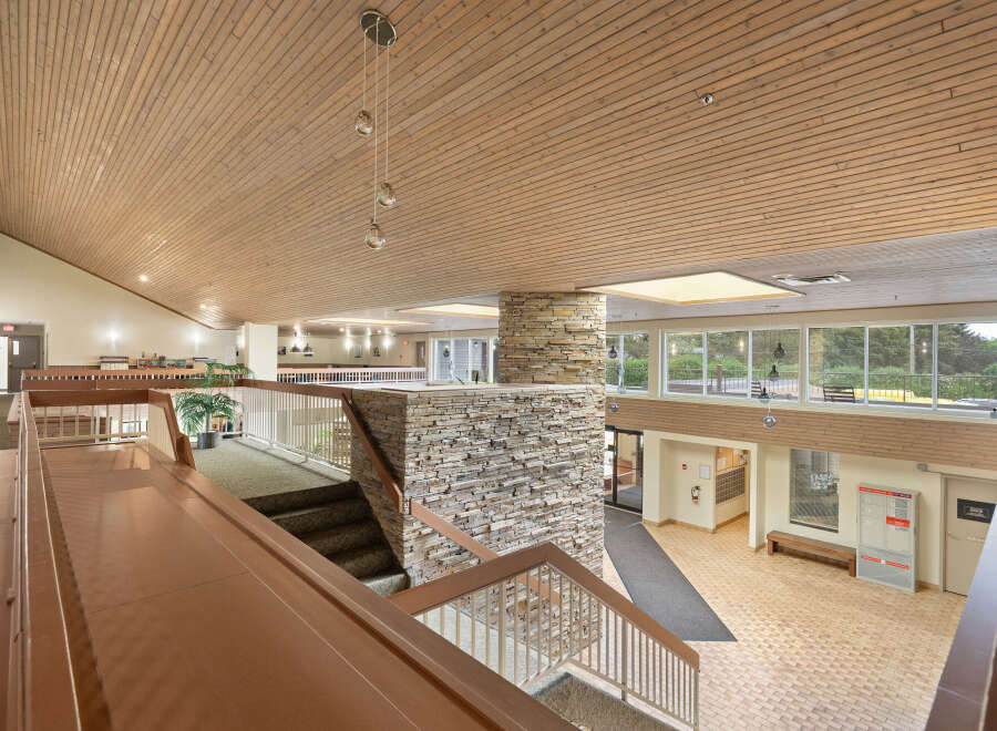 Experience a warm and inviting atmosphere in this multi-level interior space, featuring a striking stone accent wall and a beautifully paneled wood ceiling.