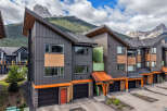 Experience modern mountain living in this stunning townhouse complex, featuring a striking architectural design with dark siding, warm wood accents, and vibrant green and copper details.