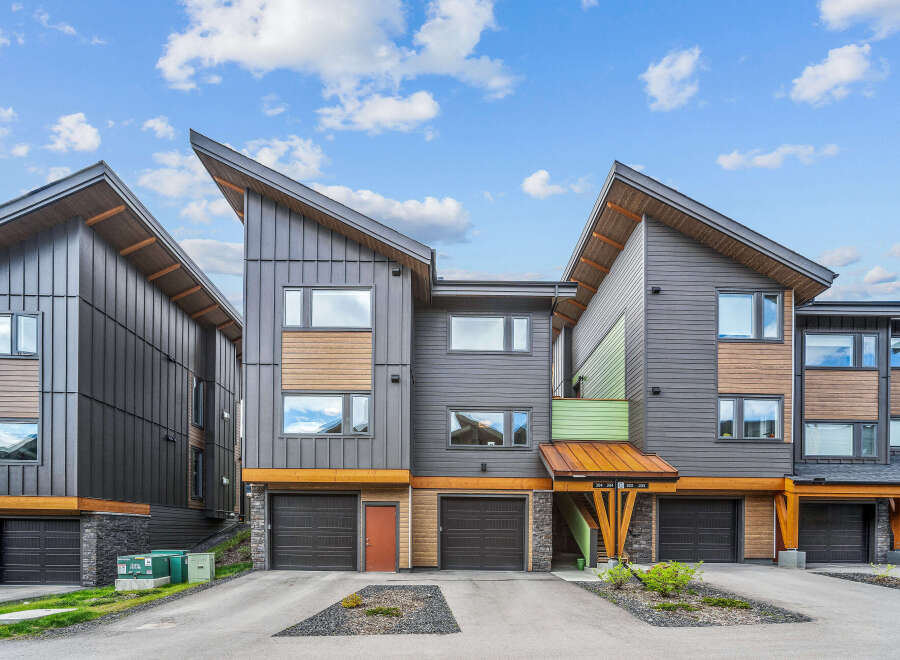 Discover modern living in this stunning townhouse complex featuring contemporary architecture with striking angled roofs and a mix of dark metal siding and warm wood accents.