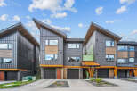 Discover modern living in this stunning townhouse complex featuring contemporary architecture with striking angled roofs and a mix of dark metal siding and warm wood accents.