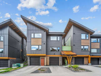 Discover modern living in this stunning townhouse complex featuring contemporary architecture with striking angled roofs and a mix of dark metal siding and warm wood accents.