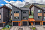Experience modern mountain living in this stunning townhouse featuring a unique architectural design with a striking angled roofline and a mix of dark metal siding and warm wood accents.