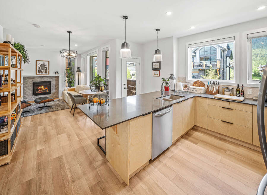 Experience modern living in this open-concept home featuring a sleek kitchen with a large island and ample cabinetry, flowing seamlessly into a cozy living area with a fireplace.