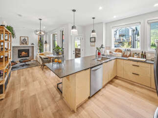 Experience modern living in this open-concept home featuring a sleek kitchen with a large island and ample cabinetry, flowing seamlessly into a cozy living area with a fireplace.