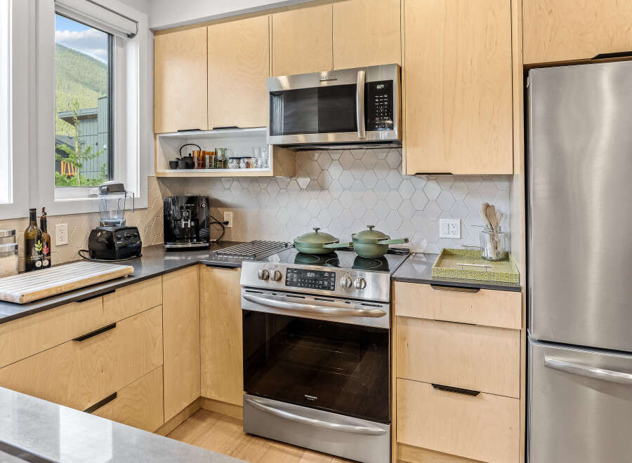 Experience modern living in this stunning kitchen, featuring sleek light wood cabinetry and a sophisticated hexagonal tile backsplash.