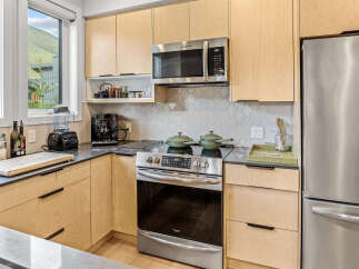 Experience modern living in this stunning kitchen, featuring sleek light wood cabinetry and a sophisticated hexagonal tile backsplash.
