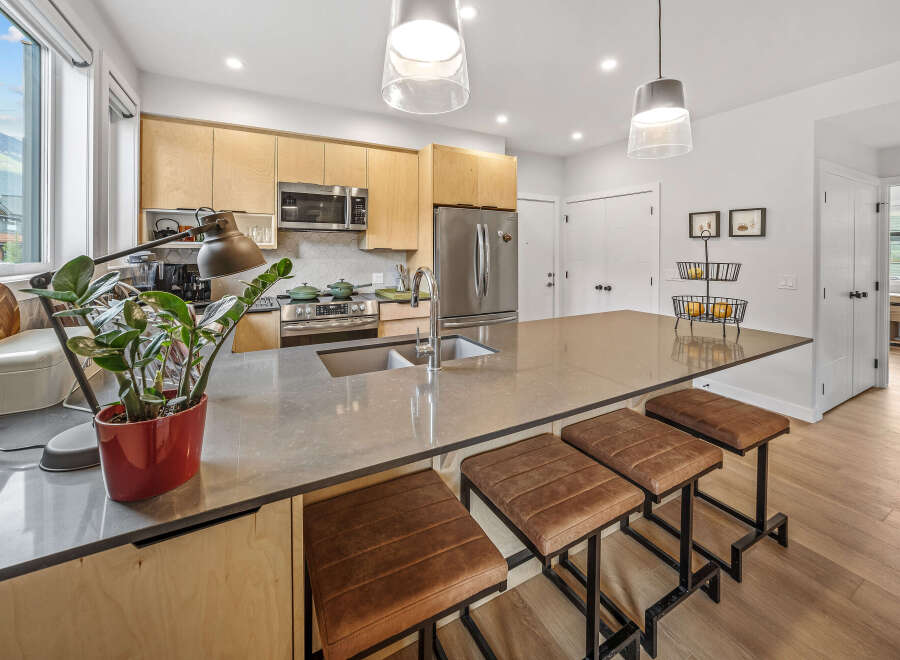 Experience modern living in this stunning kitchen featuring sleek, light wood cabinetry and a spacious quartz island perfect for entertaining.