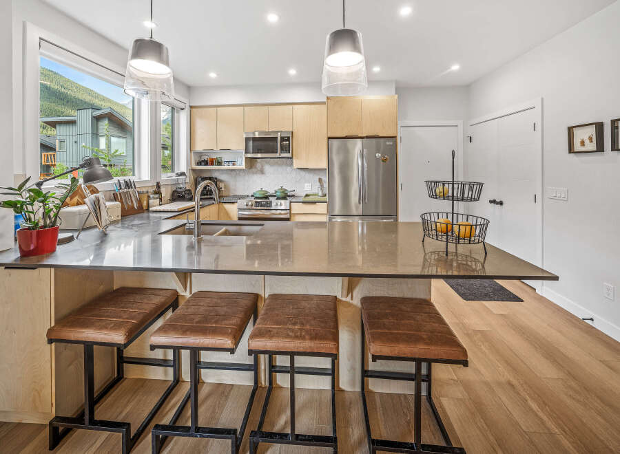 Experience modern living in this stunning kitchen featuring sleek cabinetry, a spacious island with bar seating, and top-of-the-line stainless steel appliances.
