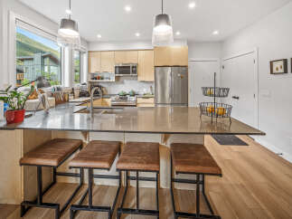 Experience modern living in this stunning kitchen featuring sleek cabinetry, a spacious island with bar seating, and top-of-the-line stainless steel appliances.