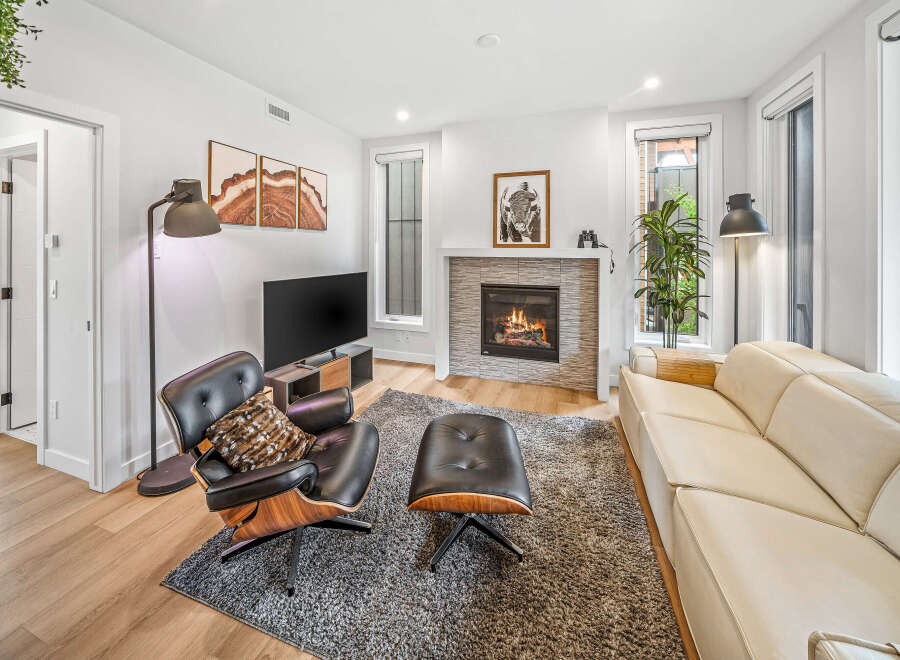 Experience modern living in this stylish living room featuring a cozy fireplace and a comfortable leather armchair with an ottoman.