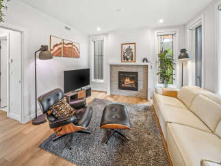 Experience modern living in this stylish living room featuring a cozy fireplace and a comfortable leather armchair with an ottoman.
