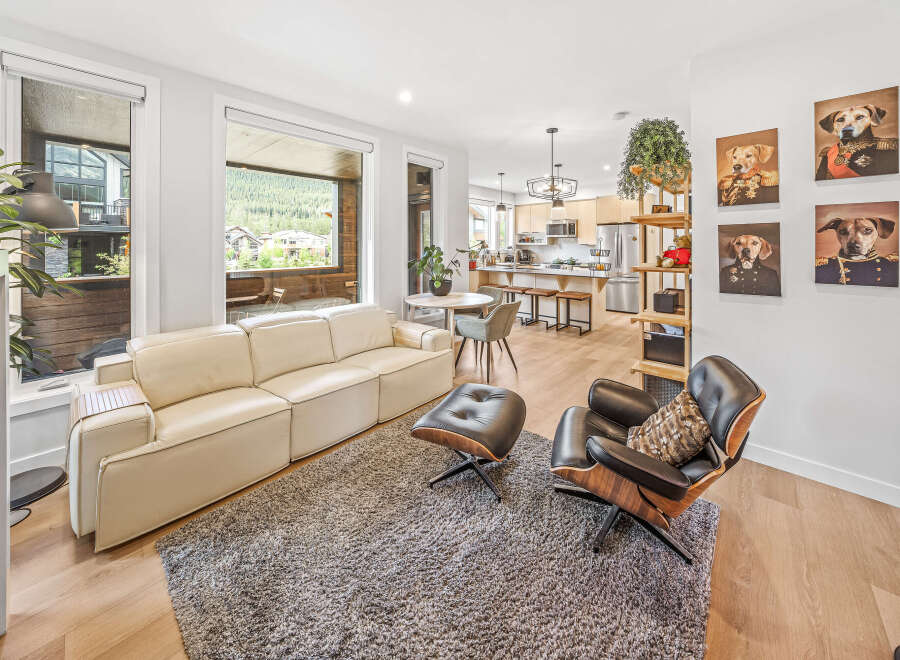 Experience modern living in this stunning open-concept space, featuring a sleek cream sofa and a stylish black leather lounge chair perfect for relaxation.