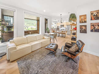 Experience modern living in this stunning open-concept space, featuring a sleek cream sofa and a stylish black leather lounge chair perfect for relaxation.