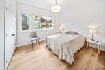 This bright bedroom features a comfortable bed with a decorative pillow and a cozy throw blanket.