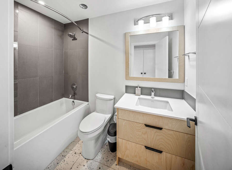 Discover modern comfort in this beautifully appointed bathroom, featuring a sleek bathtub with contemporary grey tile surround.