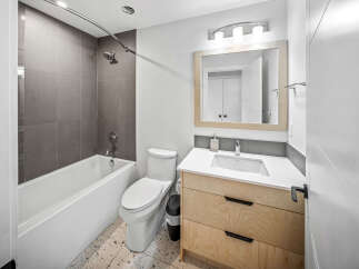 Discover modern comfort in this beautifully appointed bathroom, featuring a sleek bathtub with contemporary grey tile surround.