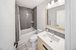 This modern bathroom features a sleek white bathtub with a grey tiled backsplash and a stylish shower curtain.