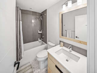 This modern bathroom features a sleek white bathtub with a grey tiled backsplash and a stylish shower curtain.