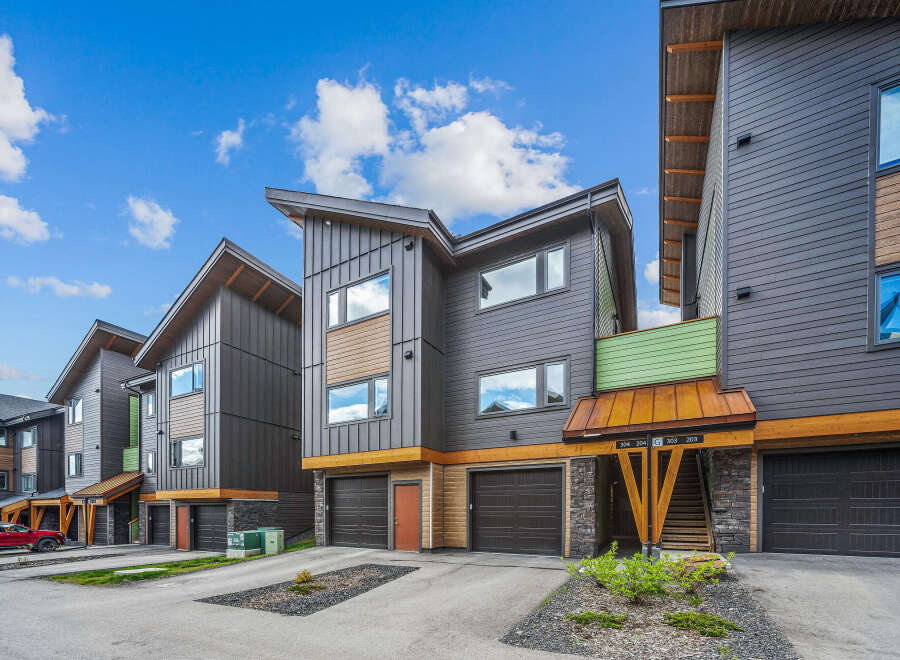 Discover modern living in these stunning townhomes featuring sleek dark siding and warm wood accents.