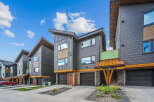Discover modern living in these stunning townhomes featuring sleek dark siding and warm wood accents.