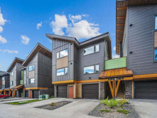 Discover modern living in these stunning townhomes featuring sleek dark siding and warm wood accents.