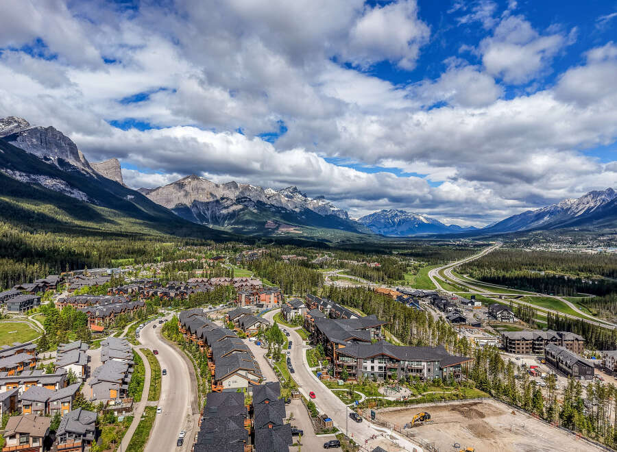 Experience mountain living in this stunning aerial view of a modern residential community nestled amidst the majestic Rocky Mountains.