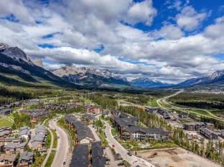 Experience mountain living in this stunning aerial view of a modern residential community nestled amidst the majestic Rocky Mountains.