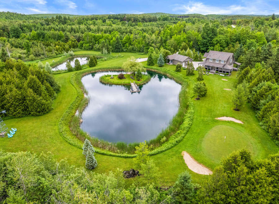 Discover this stunning estate featuring a private pond with a charming island and dock, perfect for serene moments.