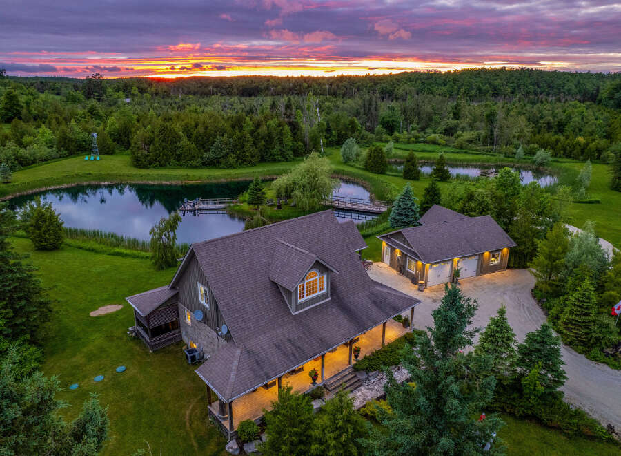 Experience serene country living with this stunning property featuring a charming home and a detached garage, nestled amidst lush greenery and tranquil ponds.