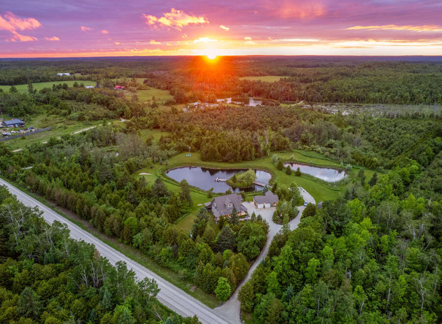 Experience serene country living with this stunning aerial view of a sprawling estate at sunset.