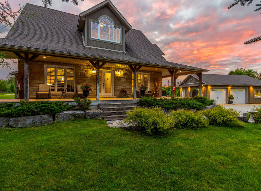 Experience luxury living in this stunning stone-clad home, featuring a welcoming wrap-around porch perfect for enjoying the picturesque sunset views.