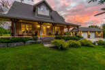 Experience luxury living in this stunning stone-clad home, featuring a welcoming wrap-around porch perfect for enjoying the picturesque sunset views.