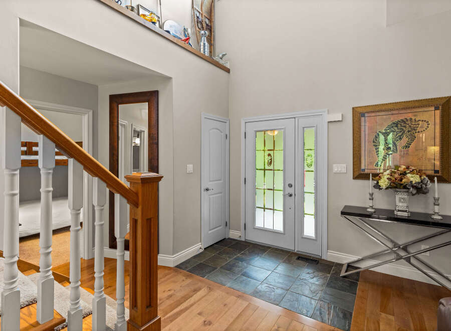 Step into a grand foyer featuring a stunning wooden staircase and elegant double doors that welcome you home.
