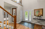 Step into a grand foyer featuring a stunning wooden staircase and elegant double doors that welcome you home.
