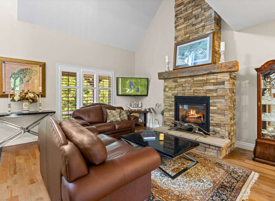 Experience luxury living in this stunning living room, featuring a grand stone fireplace as the centerpiece.