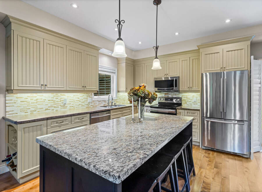 This spacious kitchen boasts custom cabinetry with beadboard detailing and elegant crown molding.